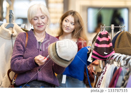 Mature woman helping a young woman choose a hat Mature woman helping a young woman choose a hat 133787535