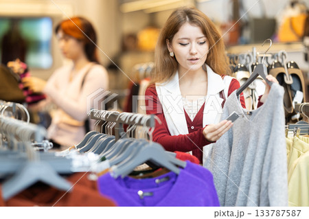 Young woman chooses sweater in clothing store 133787587