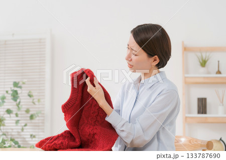 セーターを見て困る女性 133787690