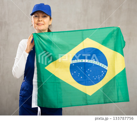 Cheerful female worker with wide grin on her face holding flag of brazil 133787756