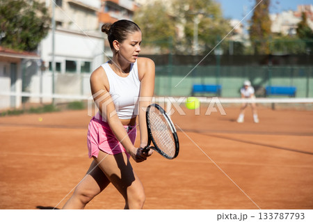 Young woman playing tennis against older woman 133787793