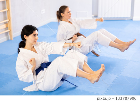 Two women in kimono doing abdominal exercises in gym 133787906