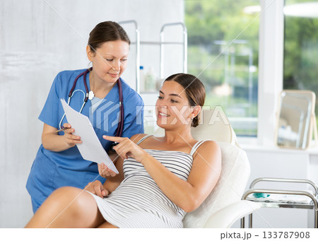 Adult female doctor shows contract to patient Adult female doctor shows contract to patient 133787908