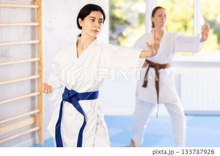 Woman in kimono standing in fight stance during group karate training 133787926