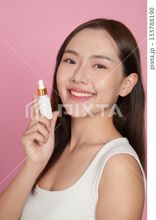 Beauty Product. Young woman holding a dropper bottle of serum with a bright smile. 133788190