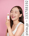 Skincare Routine. Young woman applying serum with a dropper, smiling brightly. 133788192