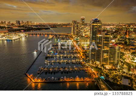 Twilight over Miami skyline and marina. Luxury yachts glowing in the Miami harbor. Sunset cruise near Miami downtown skyscrapers. Aerial night view of Miami Beach at dusk. 133788825