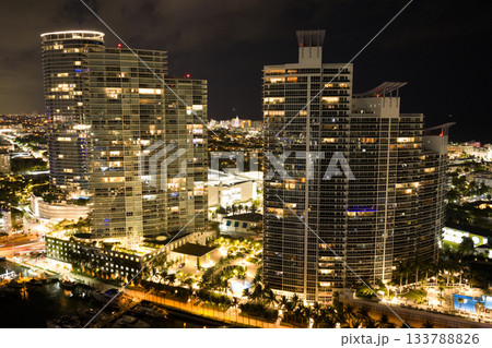 Aerial night view of Miami coastline. Twilight skyline above the Miami oceanfront. Miami Beach waterfront with dramatic sky. 133788826