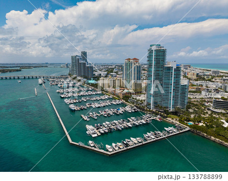 Luxury yacht docked at Miami marina. Aerial view of coastline in Miami. Sailboat cruising along the Miamis shore. Miami skyline above harbor. Famous Miami Beach marine from above. Marina with yachts. Luxury yacht docked at Miami marina. Aerial view of coastline in Miami. Sailboat cruising along the Miamis shore. Miami skyline above harbor. Famous Miami Beach marine from above. Marina with yachts. 133788899