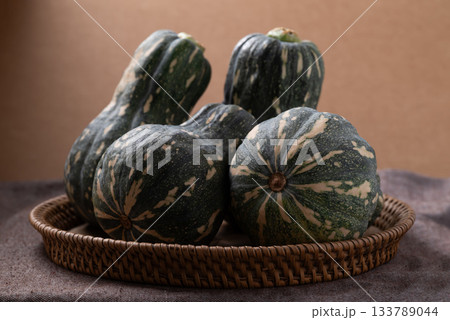 Green butternut squash pumpkin in basket on brown background Green butternut squash pumpkin in basket on brown background 133789044