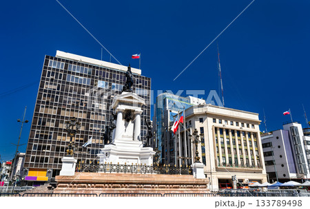 Historic Monument to the Heroes of Iquique stands in Plaza Sotomayor of Valparaiso, Chile. Bronze statues and white pedestal honor naval heroes under clear blue sky near Chilean Navy headquarters 133789498