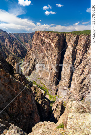 View of the massive Painted Wall in Black Canyon of the Gunnison National Park. White pegmatite dikes create stripes on the dark, sheer cliff. The Gunnison River is visible below View of the massive Painted Wall in Black Canyon of the Gunnison National Park. White pegmatite dikes create stripes on the dark, sheer cliff. The Gunnison River is visible below 133790130