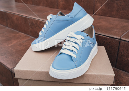 Elegant blue leather womens shoes blank product for branding displayed on recycled cardboard box. New casual female sneakers no-brand footwear e-commerce. No logo product unbranded fashion 133790645