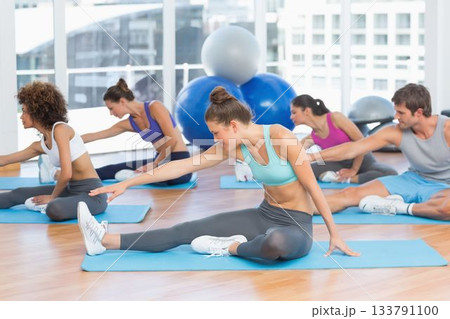 Group of adults are stretching legs on blue mats in flat design studio with stability balls Group of adults are stretching legs on blue mats in flat design studio with stability balls 133791100