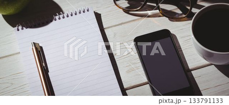 Notepad by smart phone on desk Notepad by smart phone on desk 133791133