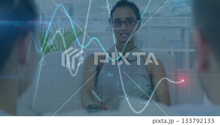 Writing Asian woman taking notes with pen at office conference table with holographic graph overlay 133792133