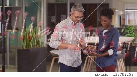 Male colleague wearing glasses and woman reviewing tablet in office lounge, network overlay 133792255