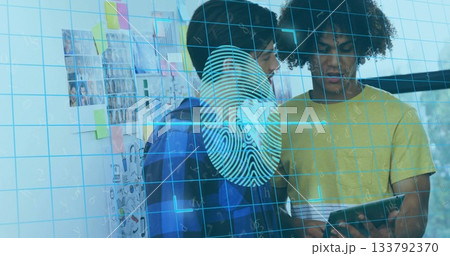 Two colleagues in blue and yellow shirts examining tablet with fingerprint grid overlay in office Two colleagues in blue and yellow shirts examining tablet with fingerprint grid overlay in office 133792370