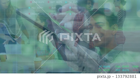 Professional holding tablet and smiling with coworkers at conference table showing stock tickers Professional holding tablet and smiling with coworkers at conference table showing stock tickers 133792881