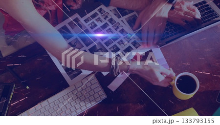 Sorting contact sheets two creatives reviewing images at studio desk, with swatches and laptop 133793155