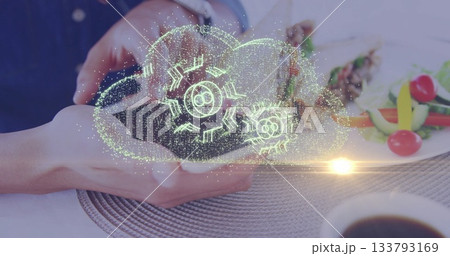 Holding smartphone projecting holographic cloud above dining table, with skewers and coffee cup Holding smartphone projecting holographic cloud above dining table, with skewers and coffee cup 133793169