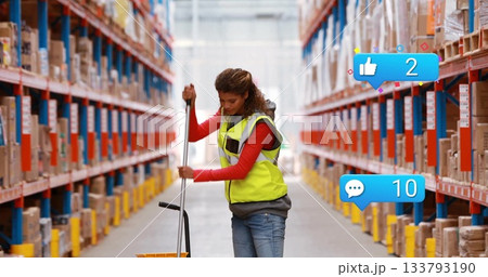 Warehouse worker wearing safety vest pushing pallet jack in warehouse aisle, with shelving racks Warehouse worker wearing safety vest pushing pallet jack in warehouse aisle, with shelving racks 133793190