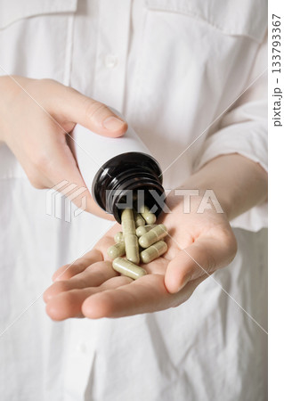 Person pouring dietary supplements or medicine into an open palm Person pouring dietary supplements or medicine into an open palm 133793367
