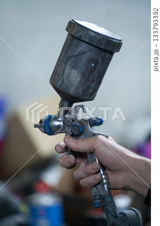 A close-up of a paint sprayer in the hand of a car mechanic A close-up of a paint sprayer in the hand of a car mechanic 133793392