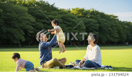 公園で芝生でレジャーシートを広げて遊ぶ4人家族 公園で芝生でレジャーシートを広げて遊ぶ4人家族 133794024