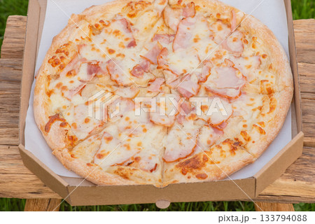 Pizza with bacon and cheese in a paper box. 133794088