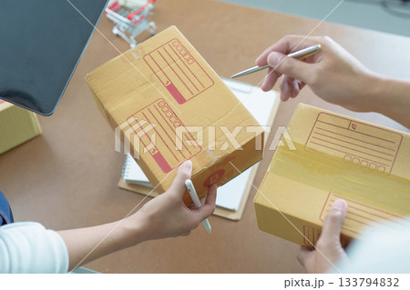 Small Business. Entrepreneurs discussing shipping details while preparing packages. Small Business. Entrepreneurs discussing shipping details while preparing packages. 133794832