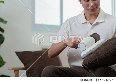 Technology and Lifestyle. Man using handheld vacuum cleaner for home cleaning. Technology and Lifestyle. Man using handheld vacuum cleaner for home cleaning. 133794897