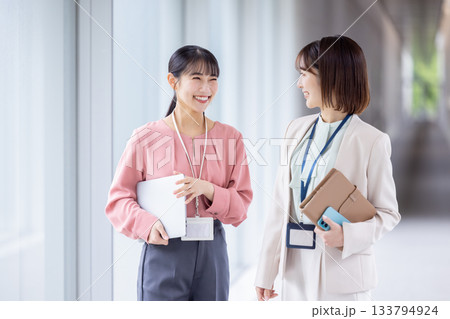 ビジネス　会話をしながら通路を歩いている女性 133794924