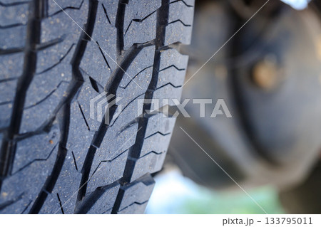 Closeup of a four-wheel drive pickup truck all-terrain tire showing worn tread patterns, dirt, and signs of rugged off-road use Closeup of a four-wheel drive pickup truck all-terrain tire showing worn tread patterns, dirt, and signs of rugged off-road use 133795011