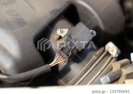 Closeup of a car air flow sensor, highlighting intricate electronic components and its role in modern engine performance and efficiency Closeup of a car air flow sensor, highlighting intricate electronic components and its role in modern engine performance and efficiency 133795045