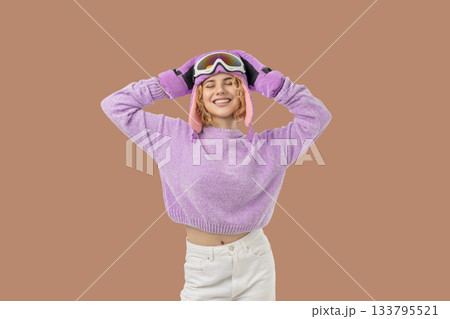 Woman poses cheerfully in winter ski gear with goggles Woman poses cheerfully in winter ski gear with goggles 133795521
