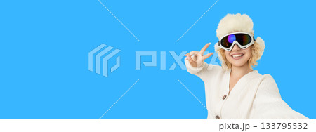 Woman in ski gear smiles and shows peace sign 133795532