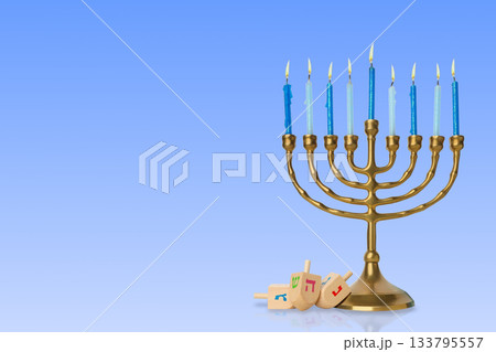 Menorah with lit blue candles beside colorful dreidels 133795557