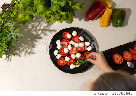 Preparing Fresh Caprese Salad in Bright Kitchen Setting 133795646