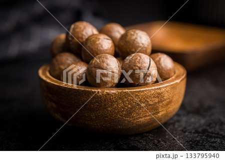 Tasty macadamia nuts in bowl on black table. Tasty macadamia nuts in bowl on black table. 133795940