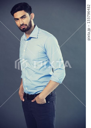 Portrait of young man standing against gray background 133796482