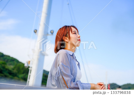 青空の下、船の上でリラックスする若い女性の横顔 133796838