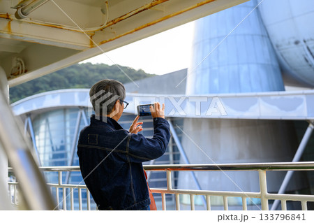 携帯電話で景色を撮影するシニア女性、隠岐の島へのフェリー甲板 133796841