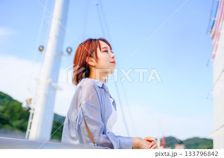 青空の下、デッキで息抜きをする若い女性。観光旅行のひととき。 133796842