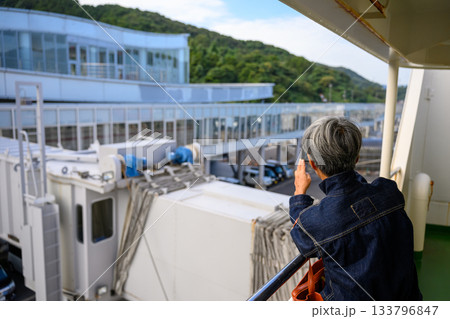 フェリー出港時に港の風景を撮影する白髪の女性 133796847