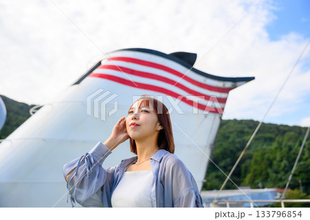 船のファンネルを背景に空を見上げる若い女性の旅行のポートレート 133796854