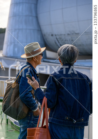 フェリーデッキで会話するデニム姿のシニア夫婦と20代女性、観光の旅立ち フェリーデッキで会話するデニム姿のシニア夫婦と20代女性、観光の旅立ち 133796865