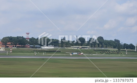 Changi Airport lush greenery spells its name beside a busy runway 133797075