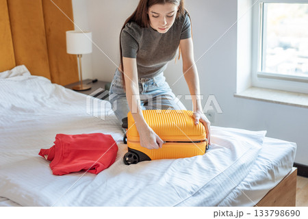 Woman packing suitcase on bed preparing for travel 133798690