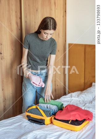 Young woman packing clothes for an upcoming trip Young woman packing clothes for an upcoming trip 133798693
